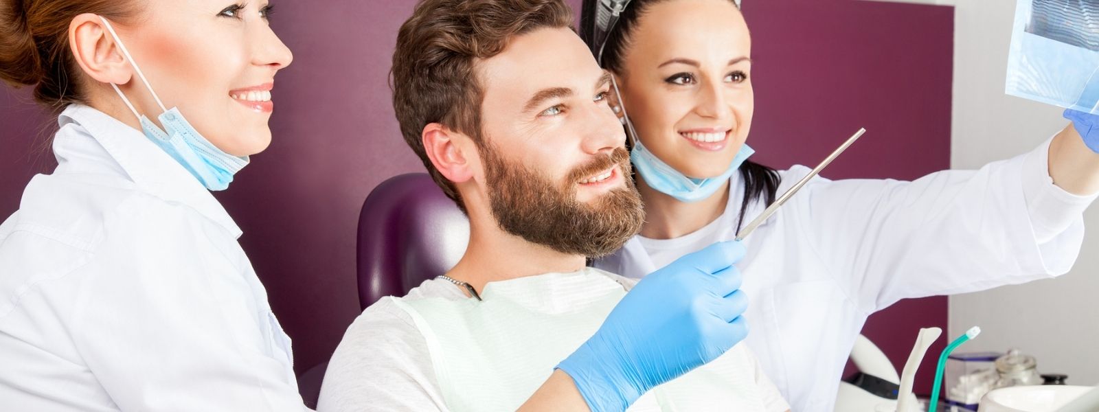 checking up on a male patient by two dentists